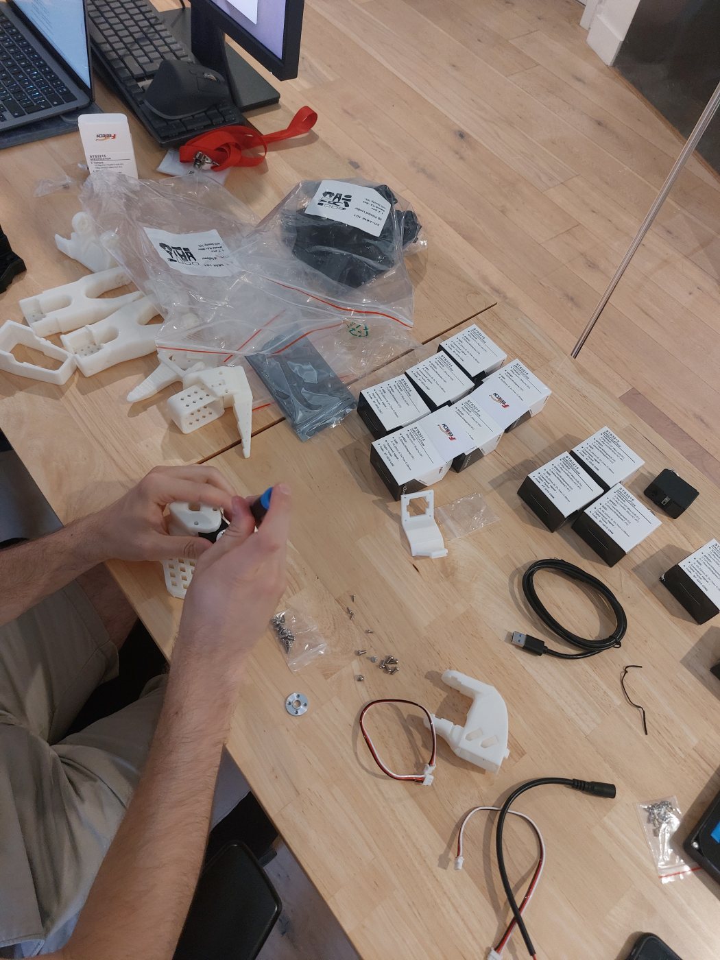 Printed parts, servos and cables laid out on a table mid-build