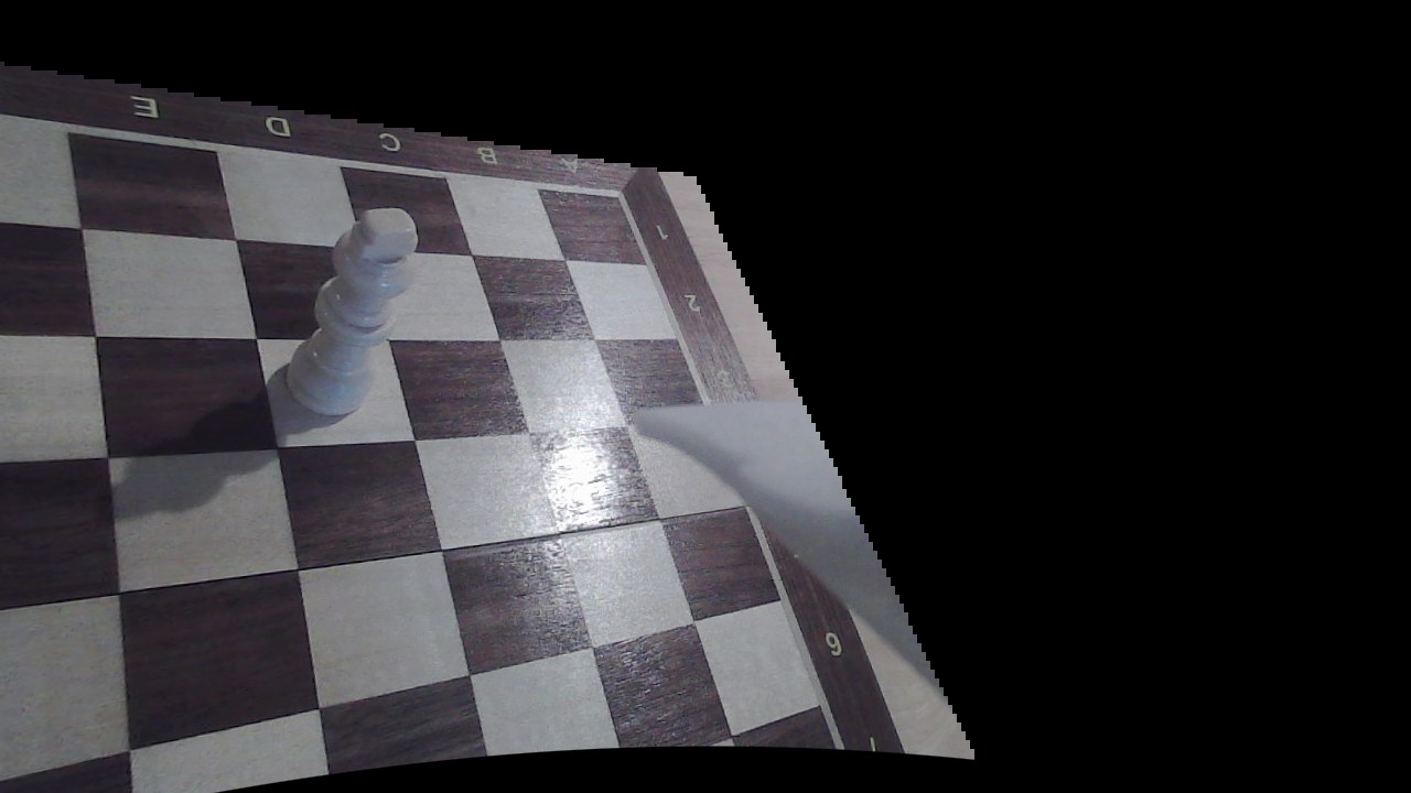 The real wrist camera view: a wooden board with wood grain, specular highlights, a shadow cast by the piece, and a wooden king